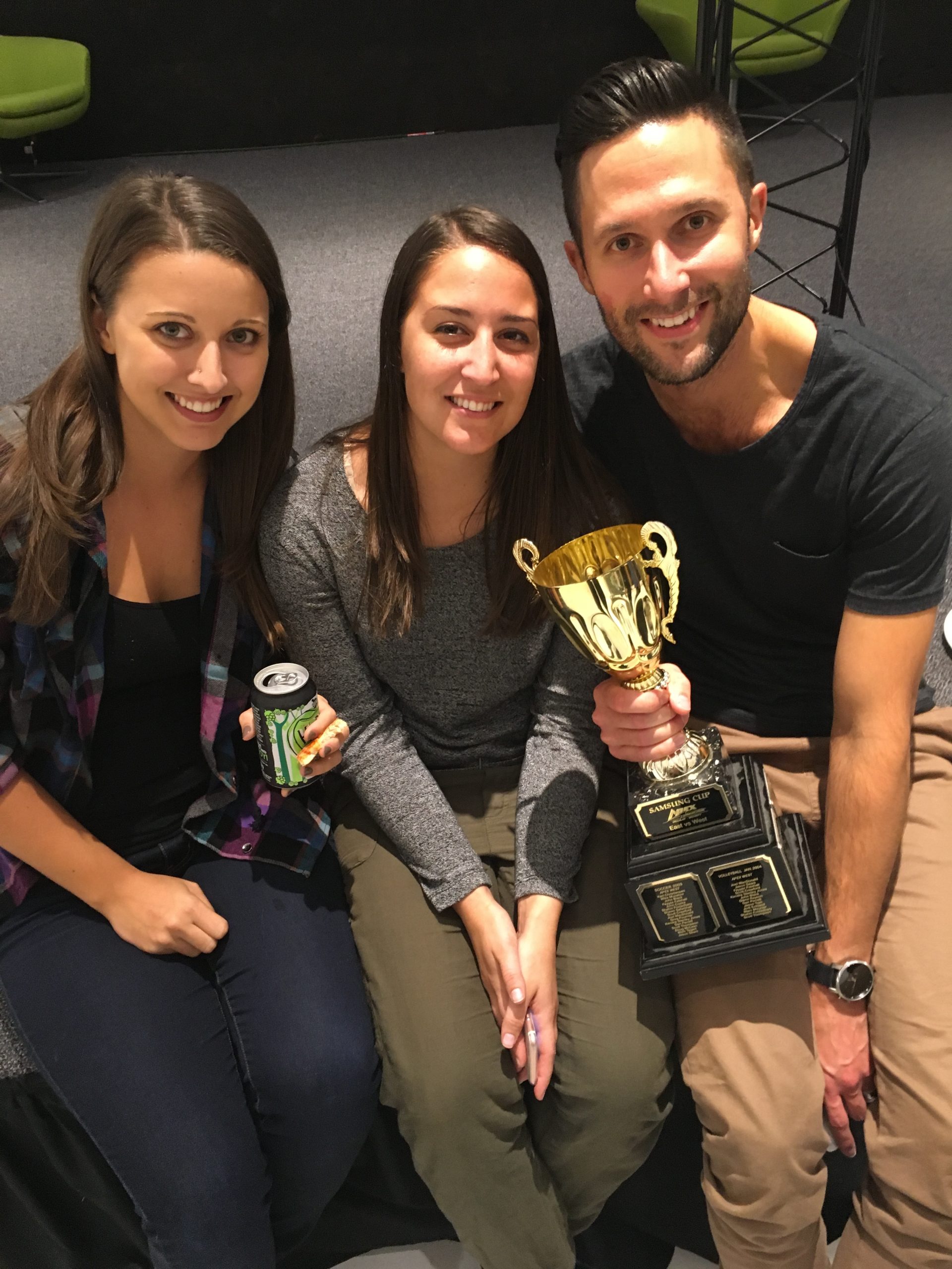 Chad Bennett holding a trophy next to two women